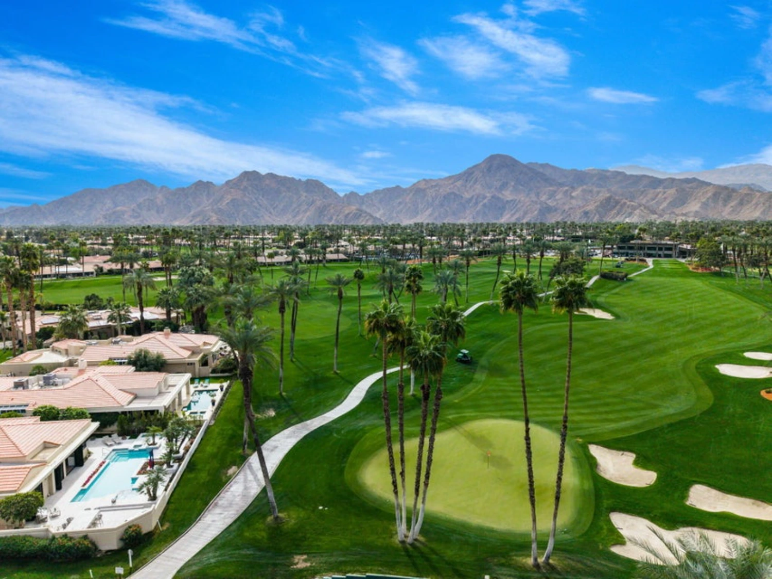 Aerial view of Desert Horizons Country Club in Indian Wells featuring the golf course, luxury homes, palm trees and dramatic mountain views.
