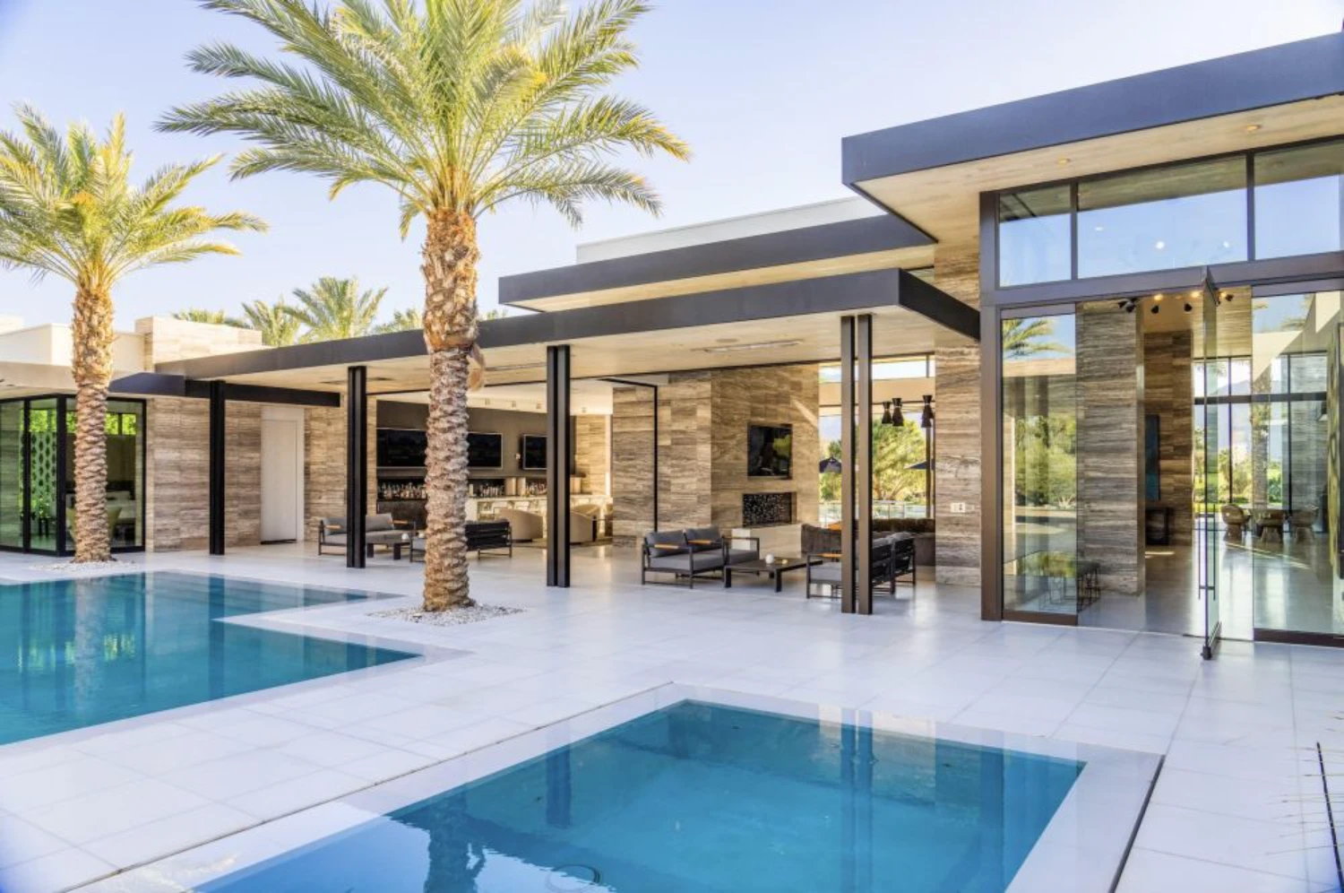 Contemporary luxury home in La Quinta featuring modern desert architecture, expansive glass walls, indoor-outdoor living and a resort-style pool.