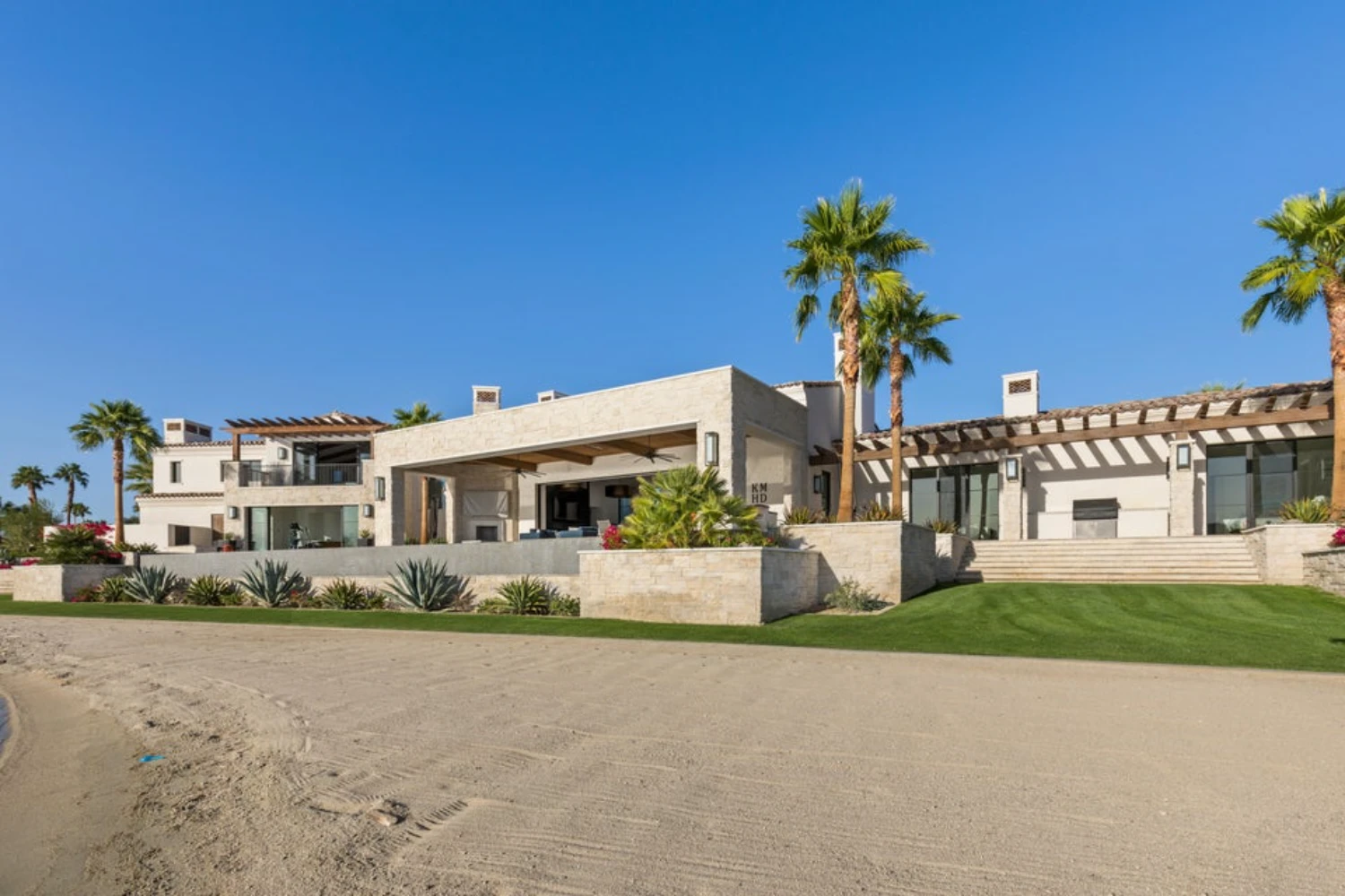 Lakeside luxury home in Indio, California featuring modern desert architecture, palm trees and waterfront living.