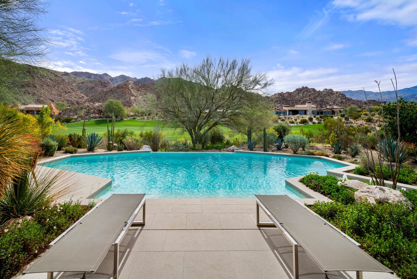 Luxury Coachella Valley home with a private pool overlooking a golf course and dramatic desert mountains.