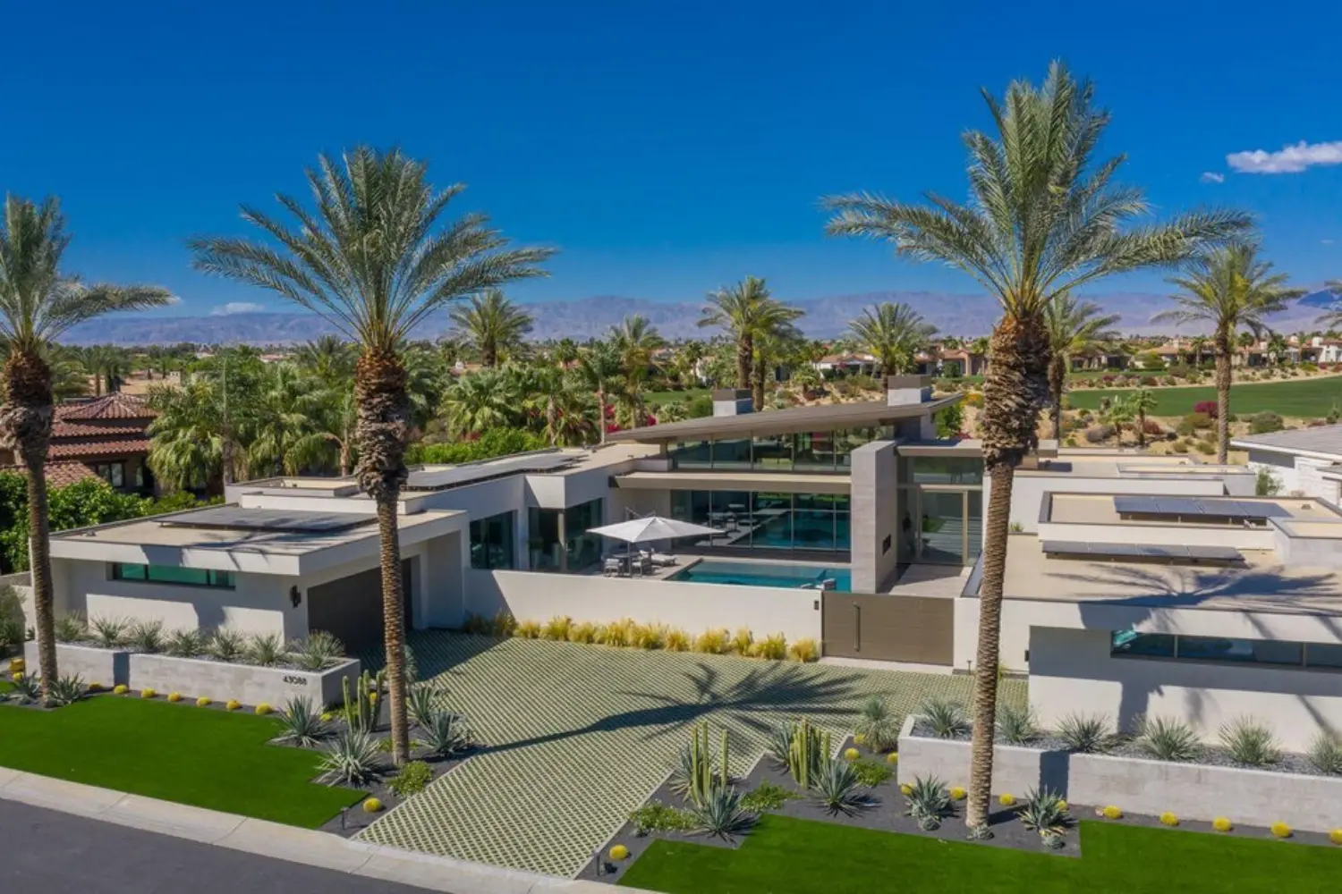 Modern luxury home at Toscana Country Club in Indian Wells, California, surrounded by palm trees and golf course views.